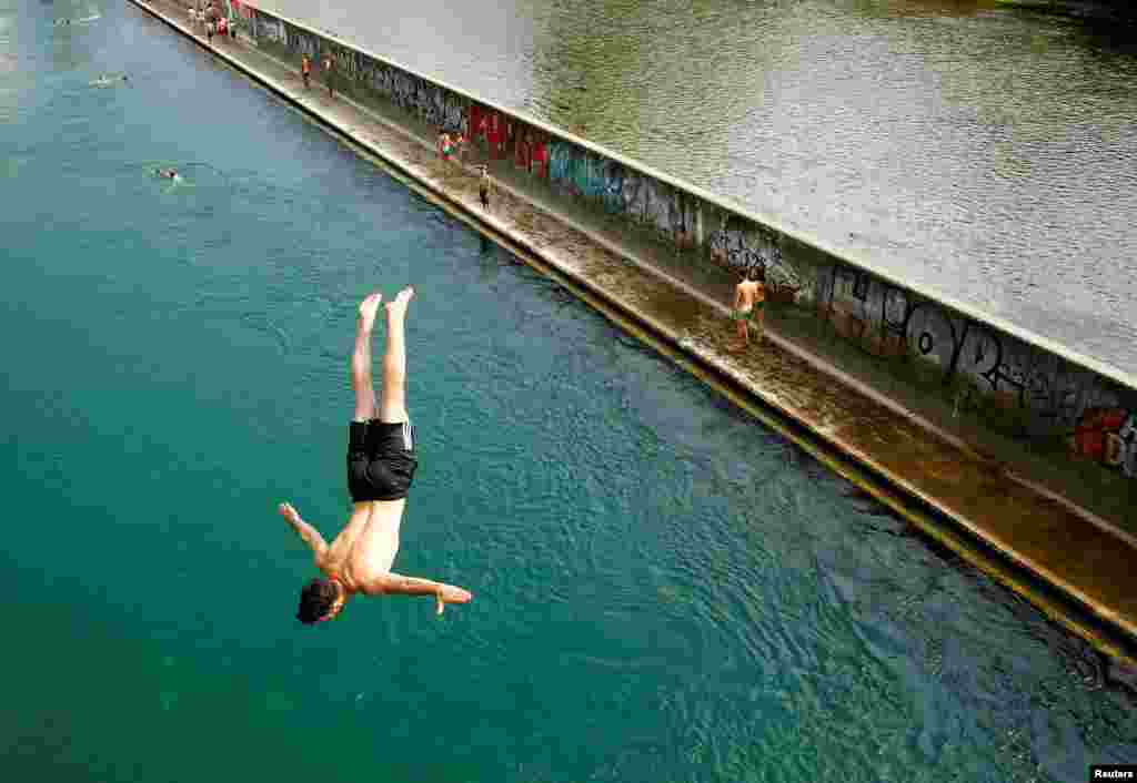 Seorang pria melompat dari sebuah jembatan ke sungai Limmat pada hari yang panas di kota Zurich, Swiss.