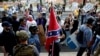 FILE - A white supremacists carries the Confederate flag as he walks past counter demonstrators in Charlottesville, Va., Aug. 12, 2017.