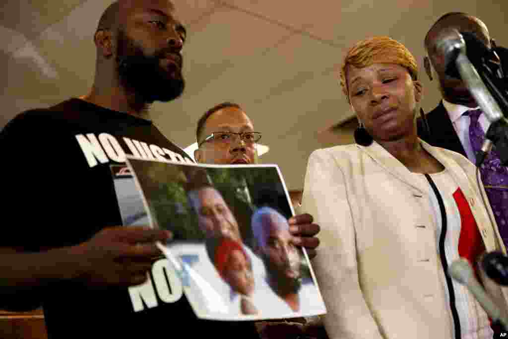 Lesley McSpadden (right), mother of 18-year-old Michael Brown, watches as Brown's father, Michael Brown Sr., holds a family picture, during a news conference, Aug. 11, 2014.