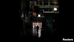 A worker walks next to halted machines at a cans' factory during a power cut in Valencia, Venezuela, April 8, 2019. 