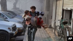An injured boy carries an injured girl as he runs towards a safe area a few minutes after the suicide bombing in Quetta, Pakistan, Feb. 6, 2016. 