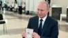 Presiden Rusia menunjukkan paspornya kepada petugas pemungutan suara saat tiba di tempat pemungutan suara di Moskow, Rusia, 1 Juli 2020.