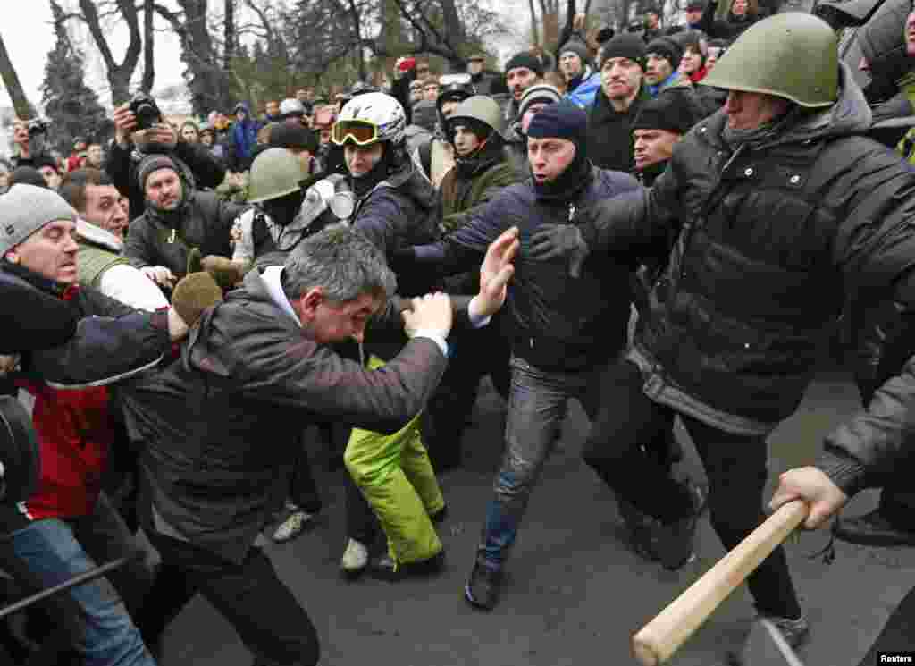 Para demonstran anti-pemerintah menyerang wakil ketua Partai Daerah Vitaly Grushevsky (kedua dari kiri, depan) di luar gedung Parlemen Ukraina di Kyiv. 