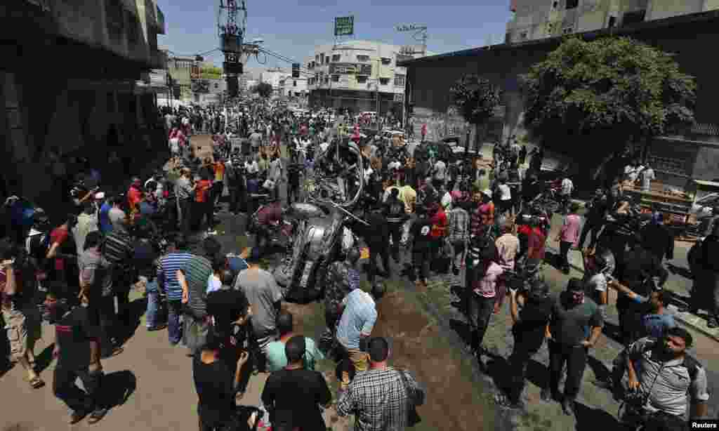 Palestinians gather around the remains of a car which police said was targeted in an Israeli air strike in Gaza City, July 8, 2014.