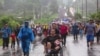 Seorang migran di kursi roda memegang bola saat ia didorong oleh sesama migran, bergabung bersama karavan mereka bertolak dari Tapachula, Meksiko menuju perbatasan AS, 6 Juni 2022. (REUTERS/Quetzalli Nicte-Ha)