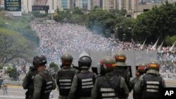 In this May 3, 2017 photo, Bolivarian National Guards stand on a highway overlooking an anti-government march trying to make its way to the National Assembly in Caracas, Venezuela.