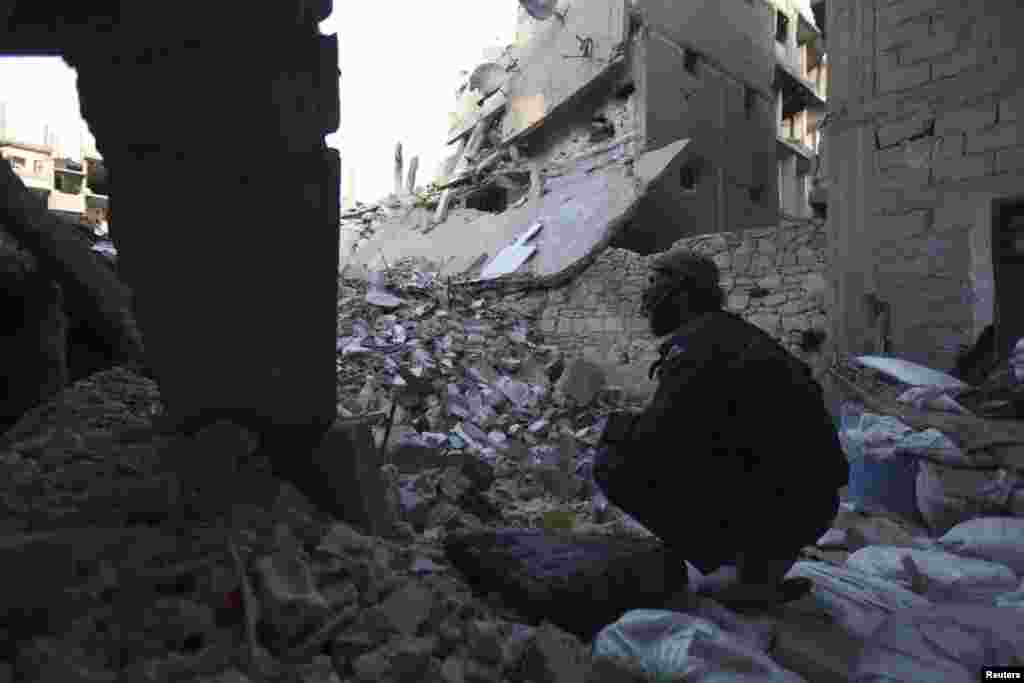 A Free Syrian Army fighter sits amid the rubble of damaged buildings in Deir al-Zor, eastern Syria, Feb. 6, 2014.