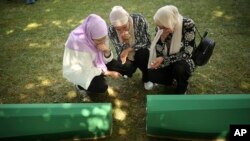 Bosnian muslim women mourn next to the coffin containing remains of their family member who is among 50 newly identified victims of Srebrenica Genocide in Potocari, July 11, 2022.