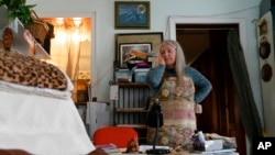 FILE - Nancy Rose, who contracted COVID-19 in 2021 and continues to exhibit long-haul symptoms, pauses while organizing her desk space, Jan. 25, 2022, in Port Jefferson, N.Y. Rose, 67, reported bouts of fatigue, brain fog and memory loss.