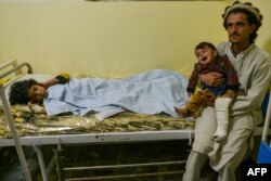 An Afghan man holds a child inside a hospital in the city of Sharan that was injured in an earthquake in Gayan district, Paktika province on June 22, 2022.
