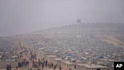 FILE - Syrians walk in a refugee camp for displaced people run by the Turkish Red Crescent in Sarmada district, north of Idlib city, Syria, Nov. 26, 2021.