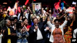 Presidential candidate Gustavo Petro, center, holds up the arm of running mate Francia Marquez on election night in Bogota, Colombia, Sunday, May 29, 2022. Marquez is making history as the country's first Black vice president. 