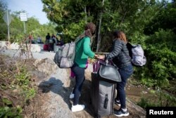 FILE - Women claiming to be from Burundi cross the U.S.-Canada border into Quebec from Champlain, New York, Aug. 3, 2017.