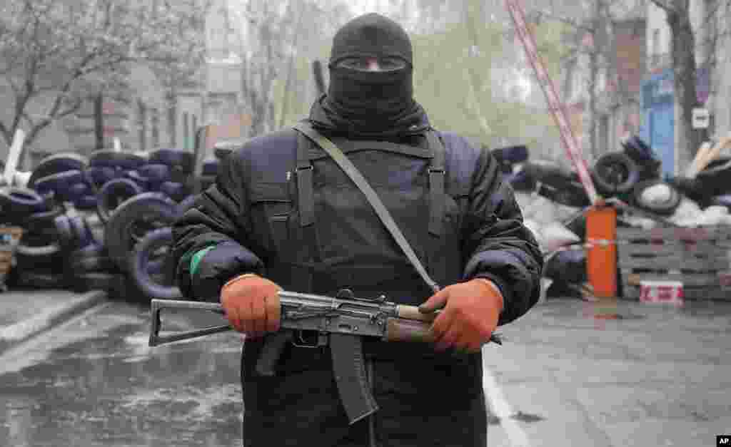 A pro-Russian gunman stands guard at a police station that was seized by pro-Russian militants, in the eastern Ukraine town of Slovyansk, April 13, 2014. 