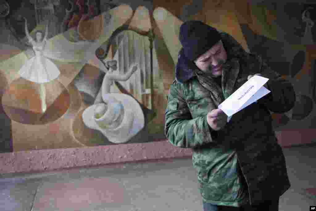 A man examines his ballot at a polling station set up inside a rebel military base for elections held by pro-Russian separatists, Donetsk, eastern Ukraine, Nov. 2, 2014. 