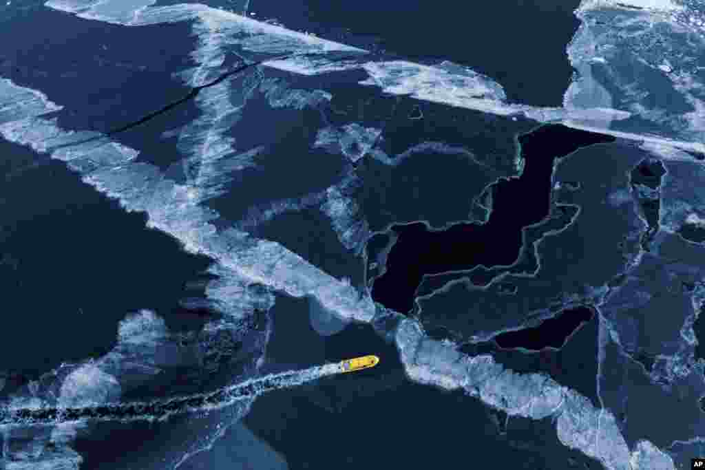 Sebuah perahu motor melaju melalui teluk laut beku di luar kota Nuuk, Greenland. (AP) 
