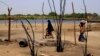 Des femmes tchadiennes passent devant des maisons détruites à la suite d'une attaque de Boko Haram dans le village de N'Gouboua, au bord du lac Tchad, le 5 mars 2015.