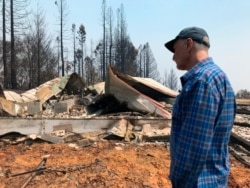 FILE - Retired teacher Charles Christianson, 67, returns to his destroyed home after a wildfire in Guerneville, Calif., Aug. 25, 2020.