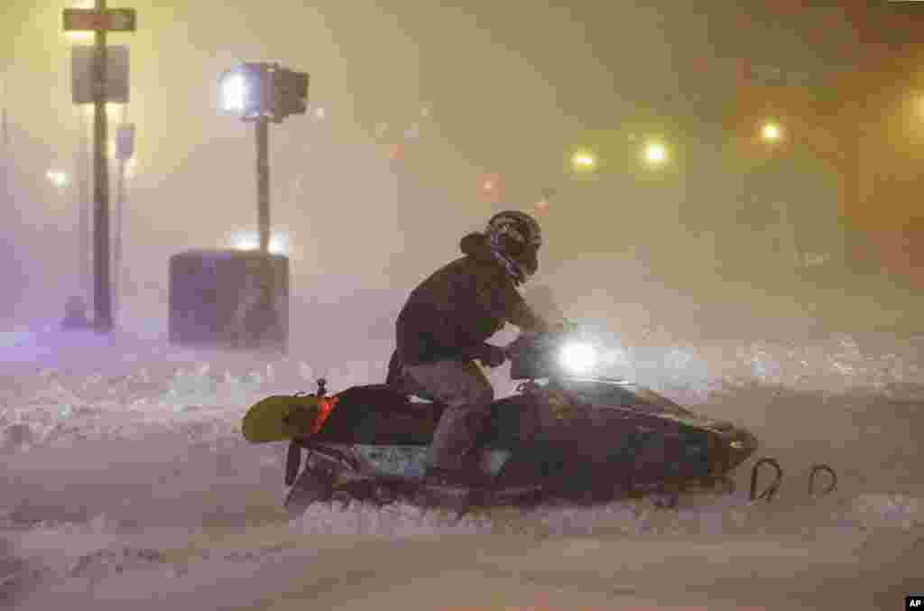 Seorang pria menggunakan mobil salju atau snowmobile di tengah badai salju di Boston, Massachusetts (27/1). (AP/Steven Senne)