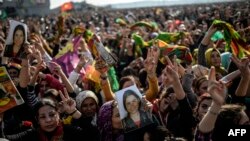 Warga Kurdi merayakan kemenangan pasukannya dan pejuang Peshmerga dalam memukul ISIS ke luar dari Kobani, sambil memegang foto pejuang yang tewas dalam konflik itu (27/1).