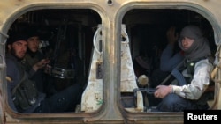 Rebel fighters ride a military vehicle with their weapons in Dahiyet al-Assad, west Aleppo city, Syria, Oct. 30, 2016. 