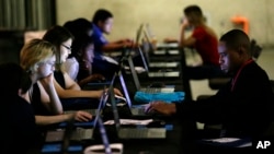 FILE - Job seekers work on their resumes during an employment event in Dallas, May 19, 2017. 