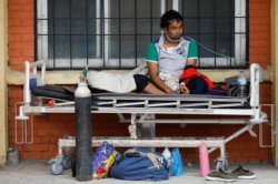 A patient receives oxygen as he waits outside the passage of a hospital due to a lack of free beds inside the hospital for coronavirus disease (COVID-19) patients, as the second major coronavirus wave surges in Kathmandu, Nepal, May 10, 2021.