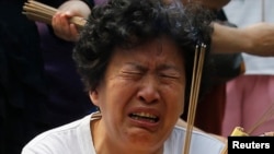 Seorang anggota keluarga penumpang pesawat Malaysia Airlines penerbangan MH370 menangis saat berdoa di Kuil Yonghegong Lama di Beijing (15/6). (Reuters/Kim Kyung-Hoon)