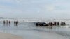 Orang-orang melakukan pencarian korban di pantai Tanjung Balau setelah sebuah kapal yang membawa para migran terbalik, di Kota Tinggi, Johor, Malaysia, 15 Desember 2021. (Royal Malaysian Army/Handout via REUTERS)