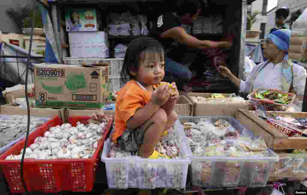 A girl sits in a garlic basket at a street market in Jakarta, Indonesia.