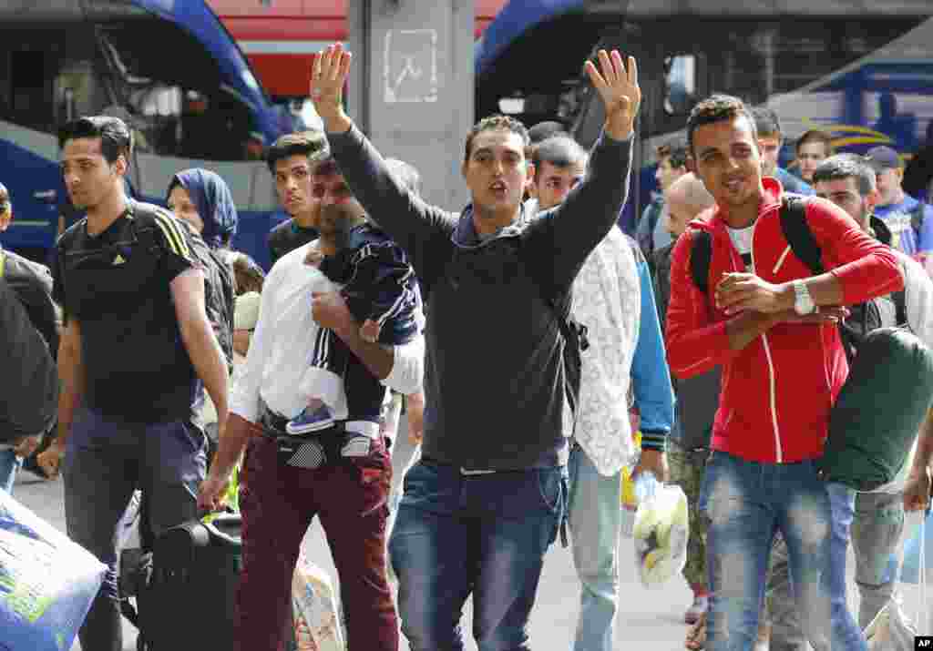 Des réfugiés saluent de la main&nbsp;à leur arrivée&nbsp;à la gare principale de Munich, en Allemagne, 5 septembre 2015.