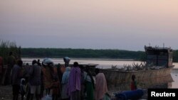 People displaced by the fighting in Bor county, stand by their belongings after arriving in the port of Minkamen, in Awerial county, Lakes state, in South Sudan, Jan. 14, 2014.