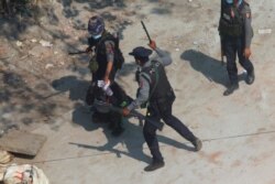 Riot police officers hold down a protester as they disperse protesters in Tharkata Township on the outskirts of Yangon, Myanmar, March 6, 2021.
