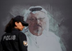 A Turkish police officer walks past a picture of slain Saudi journalist Jamal Khashoggi prior to a ceremony, near the Saudi Arabia consulate in Istanbul, marking the one-year anniversary of his death.