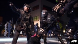 Portland police and Oregon State Patrol officers work together to arrest a protester during a protest against racial injustice and police brutality on Aug. 11, 2020. The city's had nightly protests for months.