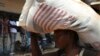 A displaced refugee woman carries a rice bag after receiving it as humanitarian aid at the airport outside the capital Bangui, Jan. 7, 2014.