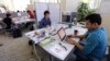 In this Thursday, June 30, 2016 photo, Babson College graduate school alumnus Abhinav Sureka, of Mumbai, India, right, types in his work space at the college in Wellesley, Mass.