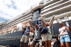 Para penumpang kapal pesiar Westerdam bersorak-sorai saat diperbolehkan turun di pelabuhan Sihanoukville, Kamboja, 14 Februari 2020.