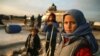 Syrian children pose for a picture as their families prepare to flee a camp for the displaced, east of Sarmada in the north of the northwestern Idlib province, February 16, 2020. (Aaref Watad/AFP)