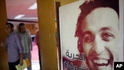 Para wartawan berjalan melewati sebuah poster yang menampilkan jurnalis foto Mesir Mahmoud Abou-Zeid, yang dikenal dengan julukan Shawkan di Kairo, Mesir, 12 Agustus 2015. Dia ditahan tanpa tuduhan saat meliput pembantaian Rabaa di Kairo.