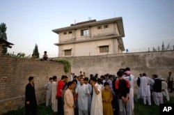 FILE - In this May 3, 2011, photo, local residents gather outside a compound where al-Qaida leader Osama bin Laden was killed by U.S. forces, in Abbottabad, Pakistan. On November 1, the CIA released a trove of documents seized during 2011 raid.