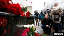 Orang-orang memberi penghormatan pada penumpang dan awak pesawat militer Rusia Tu-154 yang jatuh ke Laut Hitam, dekat tempat peringatan seadanya yang dibuat di luar markas Alexandrov Ensemble, yang juga dikenal sebagai Koor Tentara Merah (25/12). Moskow, Rusia (foto: REUTERS/Sergei Karpukhin)