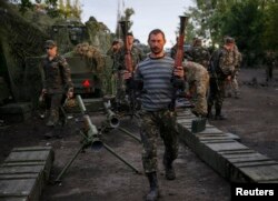 Ukrainian servicemen carry weapons, seized from pro-Russian separatists, near Slaviansk, July 8, 2014.
