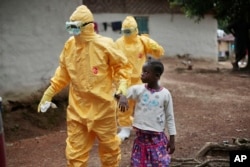 FILE - Nowa Paye, 9, is led to an ambulance after showing signs of Ebola infection in Freeman Reserve, a village 30 miles north of Monrovia, Liberia.