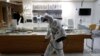 A worker wearing protective gear sprays disinfectant as a precaution against the new coronavirus in an eyeglass shop at a department store in Seoul, South Korea, March 2, 2020. 