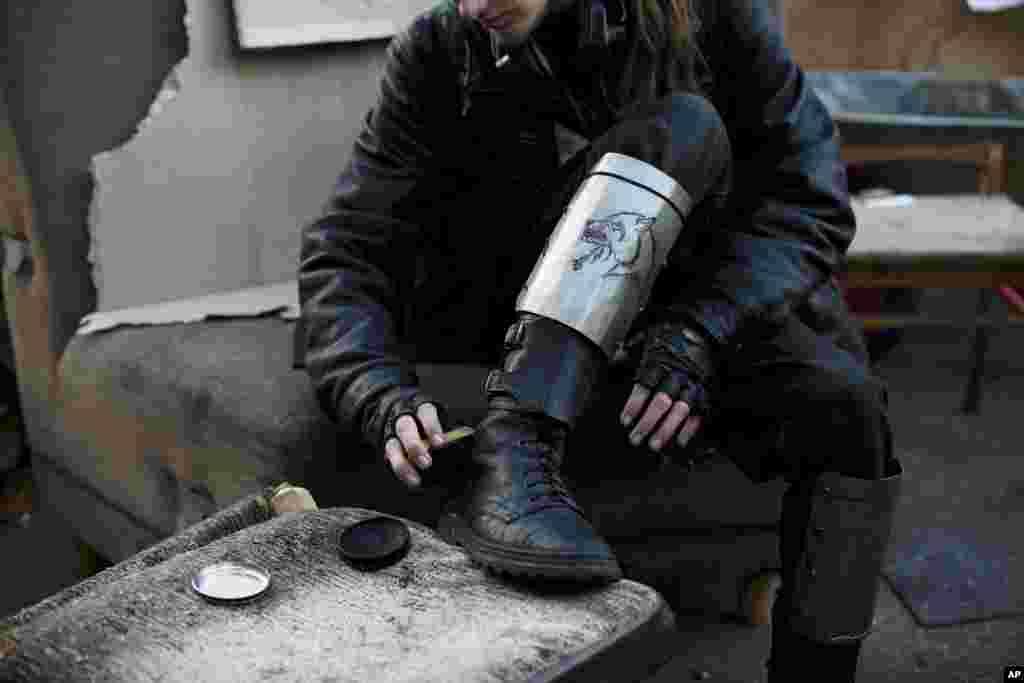 Anggota kelompok pertahanan diri sukarela menyikat sepatunya di Kyiv, Ukraina (11/3). (AP/David Azia)