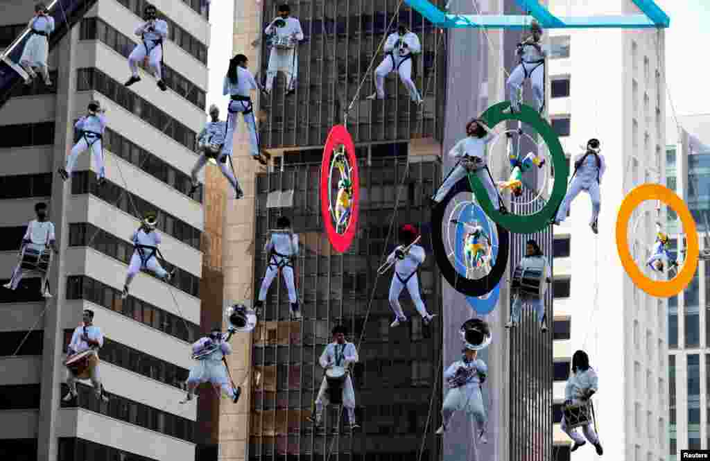 Acrobats on Olympics rings and musicians perform as the Olympic torch is relayed along Paulista Avenue in Sao Paulo's financial center, Brazil.