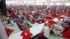 FILE - Garment workers sew clothes in a factory as they wait for a visit by Prime Minister Hun Sen outside of Phnom Penh, Cambodia, Wednesday, Aug. 30, 2017. (AP Photo/Heng Sinith)
