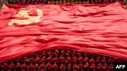 FILE - University students display the flag of the Communist Party of China to mark the party's 100th anniversary, in Wuhan in China's central Hubei, Sept. 10, 2021.