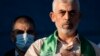 Yahya Sinwar, pemimpin Hamas Palestina di Jalur Gaza, meletakkan tangannya di dada di atas panggung setelah menyapa para pendukungnya dalam sebuah unjuk rasa pada 24 Mei 2021, di Kota Gaza, Jalur Gaza. (Foto: AP)